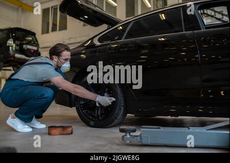 Un employé de la station-service a enduit le pneu de la voiture de noir brillant Banque D'Images