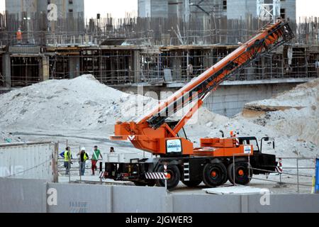 Giza, Egypte, 23 mai 2022: Une grue montée sur camion sur le site de construction de nouveaux bâtiments de la ville de Zed Z avec des travailleurs autour de lui, ville de Sheikh Zayed, acr Banque D'Images