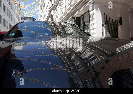 Hambourg, Allemagne. 13th juillet 2022. Les lanternes pendent au-dessus d'une rue dans le centre-ville et reflètent un véhicule. Les lanternes décorent des sections de rue dans le cadre de l'ouverture des jardins d'été de Hambourg. Credit: Julian Weber/dpa/Alay Live News Banque D'Images