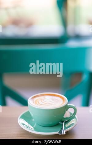 Café d'art latte chaud dans une tasse verte sur une boisson aromatique de table en bois Banque D'Images