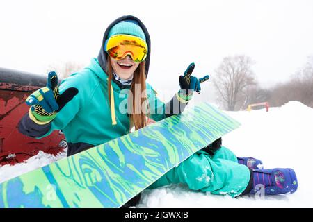 Portrait de la belle jeune fille heureuse snowboarder avec snowboard. Banque D'Images