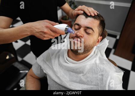 Master barber enlève les cheveux du nez de l'homme avec la tondeuse Banque D'Images