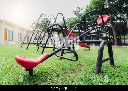 Red seesaw dans l'aire de jeux. Terrain de jeu pour les enfants. Balançoire ou fourre-tout en plastique, balançoire et toboggan à l'aire de jeux extérieure Banque D'Images