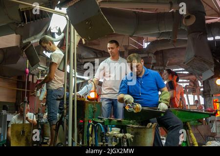 Beryozauka, Bélarus - 07 mars 2022 : une équipe de souffleurs en verre travaille à la fabrication de vases et de lunettes en verre. Jusqu'à 20 travailleurs peuvent être impliqués Banque D'Images