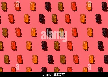 Motif composé d'ours en gelée colorés sur fond de corail. Pose à plat. Concept minimal Banque D'Images