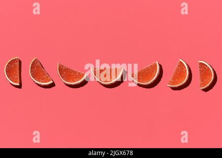 Motif composé de fruits confits colorés orange citron sur fond de corail. Pose à plat. Concept minimal Banque D'Images