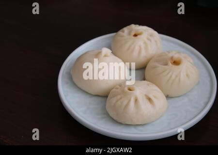 Fermez une assiette de petits pains de porc chinois poêlés (Sheng Jian Bao) sur la table. Cuisine traditionnelle Banque D'Images