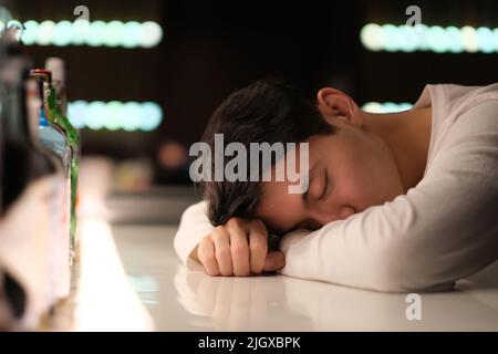 Un beau jeune asiatique ivre au comptoir le soir Banque D'Images