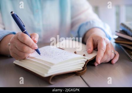 Gros plan des mains de la femme blanche écrivant dans un journal Banque D'Images