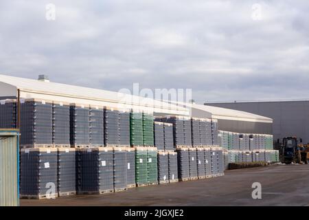 Entrepôt extérieur avec des emballages de bouteilles brunes et vertes pour mettre de la bière en bouteille sur le territoire de la brasserie. Les bouteilles sont emballées sur des palettes et c Banque D'Images