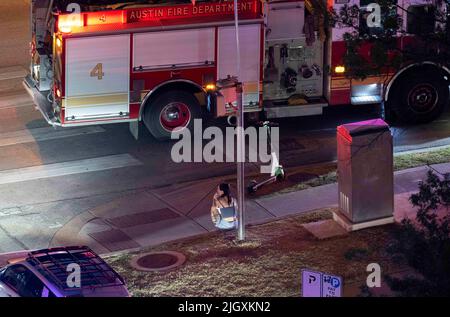 Austin Texas USA, juillet 2022 : une femme est assise sur le trottoir à la suite d'un accident de voiture au coin de 12th et dans le centre-ville de Guadalupe où un homme a été transporté à l'hôpital. Les circonstances de l'accident et l'implication de la femme dans la situation sont inconnues. ©Bob Daemmrich Banque D'Images