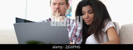 Homme d'âge moyen et femme latino-américaine regardent un film impressionnant en ligne Banque D'Images