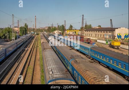 Marioupol, Ukraine - 15 juillet 2021: Trains de voyageurs garés à la gare, Azovstal en arrière-plan. Lors de l'invasion russe d'Ukrain en 2022 Banque D'Images