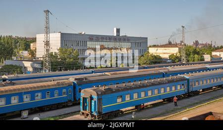 Marioupol, Ukraine - 15 juillet 2021: Gare de passagers avec des trains garés, Azovstal en arrière-plan. Lors de l'invasion russe de l'Ukraine en 2022 Banque D'Images