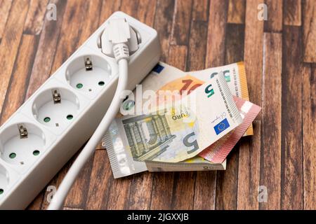 Billets en euros à côté d'une prise d'alimentation. Image symbolique pour un prix élevé de l'électricité. Augmentation des coûts énergétiques en raison des effets de l'inflation. Multisocket Banque D'Images