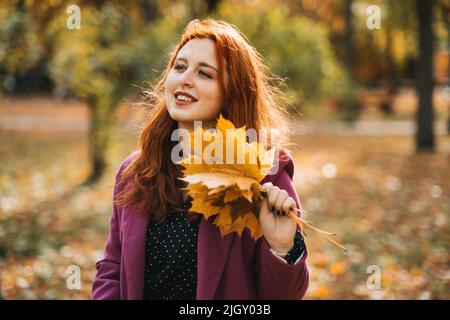 Mode d'automne, style de tons de terre, palette de couleurs d'automne vives. Portrait d'une fille aux cheveux rouges en manteau violet Banque D'Images