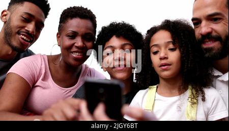 Une famille de race ethniquement mixte regardant un smartphone Banque D'Images