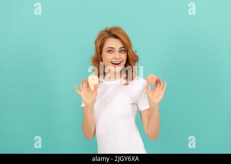 bonne femme tient doux macaron cookie français sur fond bleu Banque D'Images