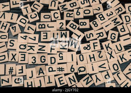 Carreaux en bois avec lettres et caractères latins sur une table (fond noir) Banque D'Images