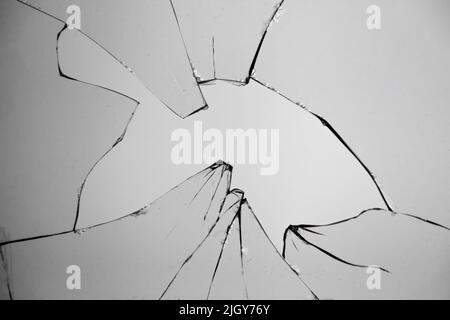 Verre brisé sur fond gris, fissures et trou dans la fenêtre. Poussière et débris sur la vitre Banque D'Images