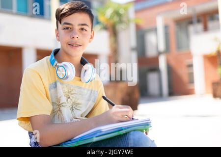 Portrait d'un adolescent étudiant qui fait ses devoirs à l'extérieur de l'école secondaire. Enseignement secondaire. Espace pour le texte. Banque D'Images