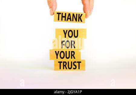 Merci pour le symbole de confiance. Concept mots Merci pour votre confiance sur des blocs de bois sur une belle table blanche fond blanc. Main d'homme d'affaires. Bus Banque D'Images