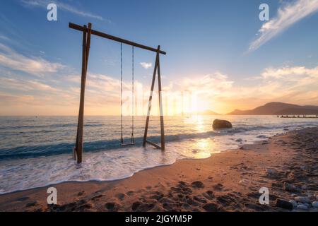 Balançoire en bois dans la belle mer bleue avec des vagues, plage de sable Banque D'Images