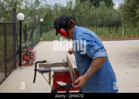 image d'un ouvrier de main coupant des planches de bois avec une scie à table. Travaux de menuiserie et de construction Banque D'Images