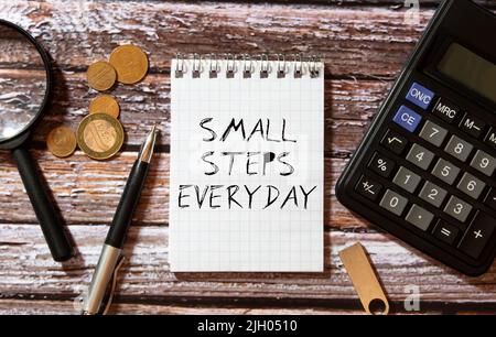 Prenez de petits pas chaque jour, les mots de texte typographie écrit sur le livre sur fond de bois. Banque D'Images