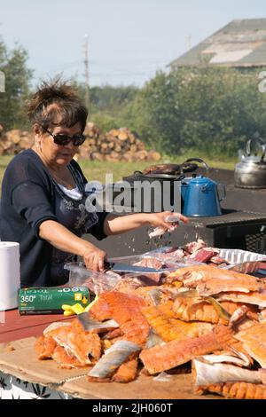 Femme autochtone dénée préparant des filets de poisson pour la fête communautaire en été, dans la communauté du nord de Deline, Territoires du Nord-Ouest, Canada Banque D'Images