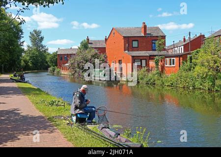 Homme pêchant avec de la canne et du rabatteur, sur le canal de Bridgewater - branche de Leigh, Wigan, Lancashire, Angleterre, Royaume-Uni, WN7 3AE Banque D'Images