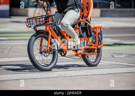 Une femme sur un vélo électrique fait un vélo le long du trottoir de la ville préférant un mode de vie actif et sain en utilisant le vélo et le vélo comme alternance Banque D'Images