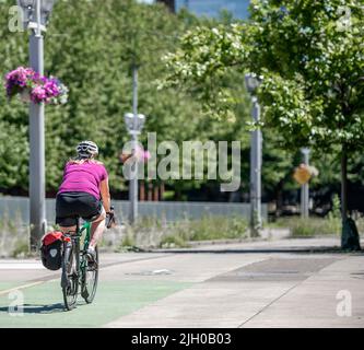 Une femme élancée à vélo fait une balade à vélo le long du trottoir en béton de la ville, préférant un mode de vie actif et sain en utilisant le vélo et le vélo comme un al Banque D'Images