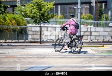 Une femme élancée à vélo fait une balade à vélo le long du trottoir en béton de la ville, préférant un mode de vie actif et sain en utilisant le vélo et le vélo comme un al Banque D'Images