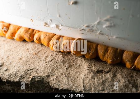 Vieille mousse de polyuréthane orange entre le mur et la fenêtre en plastique gros plan Banque D'Images