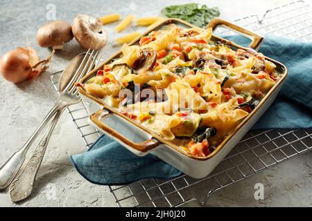 Grand angle de penne cuite au four avec fromage et champagnes servis dans une casserole avec ustensiles pour le déjeuner à table Banque D'Images