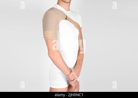 Orthèses ou accolades de l'articulation de l'épaule isolées sur fond blanc. Un homme dans un bandage orthopédique de soutien sur ses bras après la chirurgie, souffrant de Banque D'Images