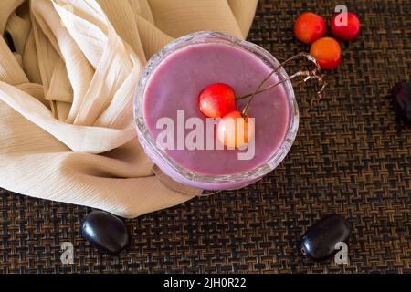Mousse Jamun ou mousse Black Plum recouverte de cerises. Dessert vegan maison frais. Vue sur le dessus, gros plan du bol isolé sur fond sombre. Espace copie. Banque D'Images