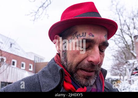 Tilburg, pays-Bas. Street Portrait d'un homme tatoué portant un chapeau lors de sa première neige de l'année flânez dans la ville, pendant une crise de Corona Lock Down. Banque D'Images