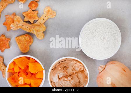 biscuits et ingrédients biologiques faits maison pour chiens sur une surface grise avec espace de copie Banque D'Images