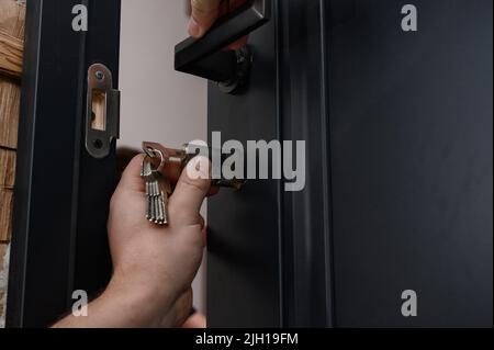 Le maître installe le noyau de la serrure de porte, le travail d'installation avec la porte. Banque D'Images