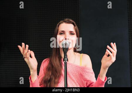 Jeune femme chantante inro le microphone gros plan Banque D'Images