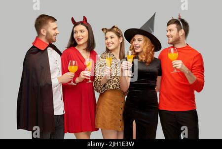 des amis heureux en costumes d'halloween sur gris Banque D'Images