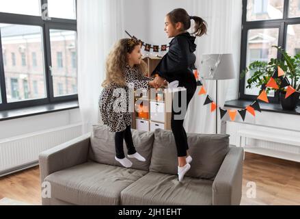 les filles en costumes d'halloween sautant sur le canapé Banque D'Images