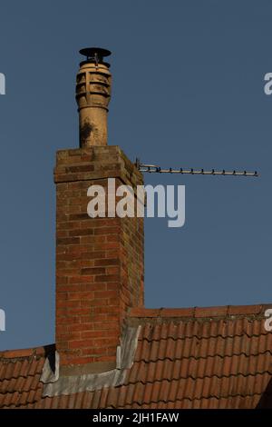 Un plan vertical de grand pot de cheminée sur la cheminée de brique rouge et le toit contre le ciel bleu Banque D'Images