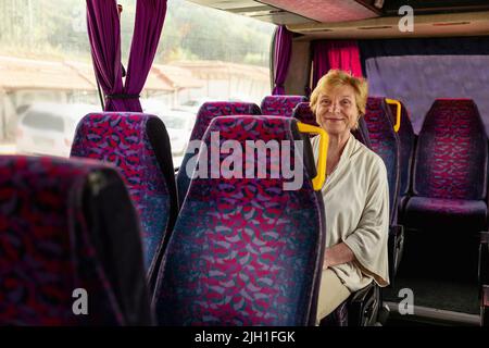 Femme âgée assise dans un bus de voyage et attendant l'excursion Banque D'Images