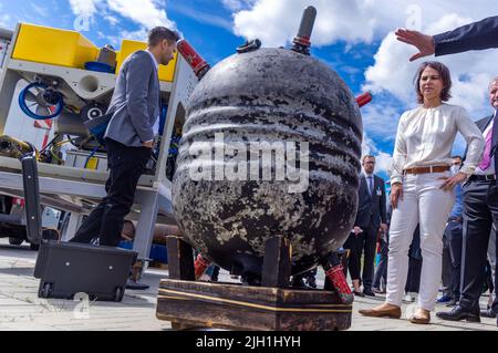 Rostock, Allemagne. 14th juillet 2022. Annalena Baerbock (Bündnis 90/Die Grünen), ministre des Affaires étrangères, se tient derrière une mine d'eau (mine de mer) de la première Guerre mondiale récupérée en mer du Nord lors de sa visite à l'Institut Fraunhofer de recherche en infographie au début de son voyage de dix jours en Allemagne. Au cours de sa tournée, la politicienne verte veut recueillir des renseignements et des impressions pour une stratégie de sécurité nationale. L'institut mène des recherches sur les effets écologiques des déchets de munitions et sur la détection des munitions dans la mer. Credit: Jens Büttner/dpa/Alay Live News Banque D'Images