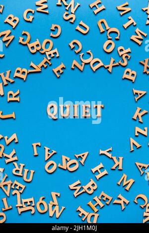 Mot QUIET fait de lettres en bois sur fond bleu clair. Concept de citations de mots de motivation. Banque D'Images