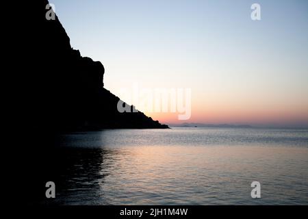 Lever de soleil sur la roche de montagne en eau de mer. Vue sur mer au lever du soleil dans une mer calme. Roche la silhouette et les reflets dorés sur l'eau ondulée Banque D'Images