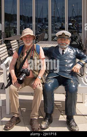 Homme âgé assis à côté de la sculpture d'un capitaine, Waterfront Quarter, Priwall, Travemünde, Lübeck, Schleswig-Holstein, Allemagne Banque D'Images